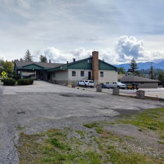 A peaceful rural building surrounded by mountainous scenery under a cloudy sky.