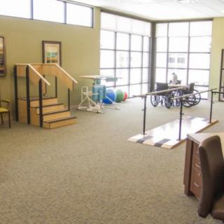 A physical therapy and rehabilitation room equipped with exercise equipment and mobility aids.
