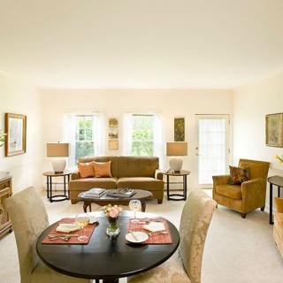 A bright and well-decorated living room featuring a dining table, sofa, and armchairs.