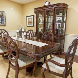 A classic dining room featuring a wooden table set with matching chairs and a glass-front cabinet.