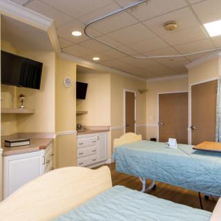 A hospital room with two beds, equipped with televisions and medical facilities.