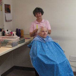A hairdresser giving a haircut to an elderly person in a salon.