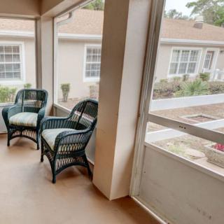 A cozy screened porch with two wicker chairs, overlooking the outside view.