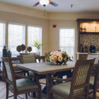 A cozy dining room with a set table, surrounded by chairs and adorned with floral decor.