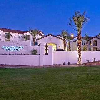 A view of an apartment complex with palm trees during the evening.