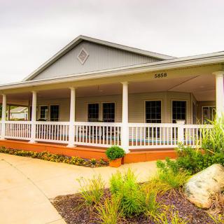 A charming house with a wraparound porch and neatly landscaped front yard.