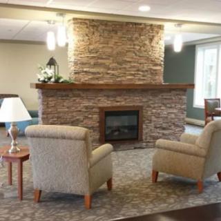 A cozy living room with a stone fireplace and two comfortable chairs.