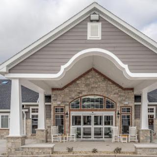 The elegant entrance of a modern building featuring a combination of stone and gray siding.