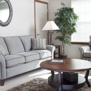 A cozy living room with a sofa, armchair, and wooden coffee table.