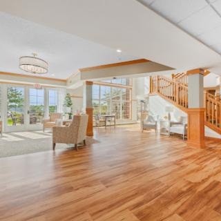 A spacious and modern living room featuring elegant wood flooring and abundant natural light.