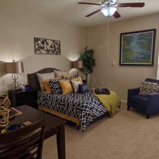 A cozy bedroom with stylish decor, featuring a bed, desk, and armchair.