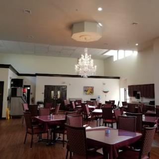A spacious dining room with elegant chandeliers and neatly arranged tables and chairs.