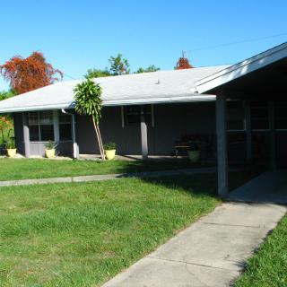 A single-story residential house with a front yard and sidewalk on a clear day.
