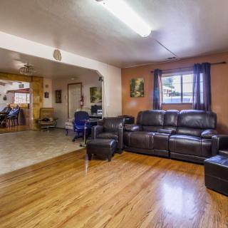 A cozy living room with a leather sofa and hardwood floors, featuring an open layout leading into the kitchen area.