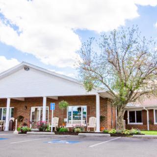 A welcoming residential building with landscaped surroundings under a partly cloudy sky.