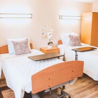 A clean and organized hospital room with two beds and bedside tables.