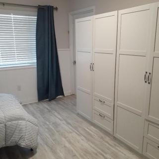 A minimalist bedroom with a large white wardrobe and blue curtains.