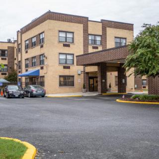 A three-story building with a covered entrance and adjacent parking lot.