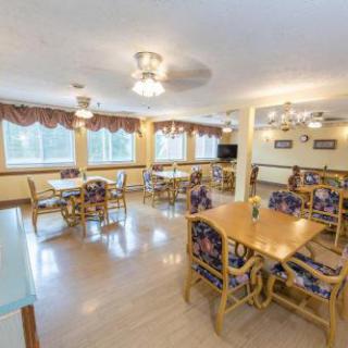 A spacious and inviting dining area with wooden tables and colorful chairs, illuminated by natural light.