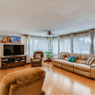 A cozy living room with comfortable seating, a television, and natural light streaming through the windows.