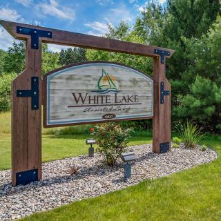 A wooden entrance sign for White Lake, surrounded by greenery.