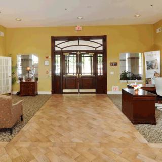 A spacious lobby with elegant wooden doors, desks, and comfortable seating.