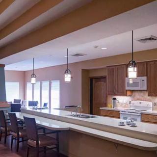 A modern kitchen and dining area featuring wooden cabinets and pendant lighting.