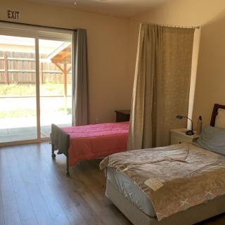 A cozy bedroom with two beds and a sliding glass door leading outside.