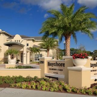 Entrance to a residential community with palm trees and a sign reading 'Bayshore'.