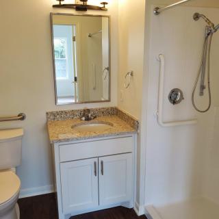 A well-lit bathroom featuring a shower, vanity with sink and mirror, and a toilet.