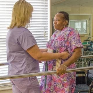 A healthcare professional assists a patient with physical therapy exercises.