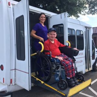 A caregiver assists a person in a wheelchair exiting a vehicle, highlighting the importance of accessible transportation.
