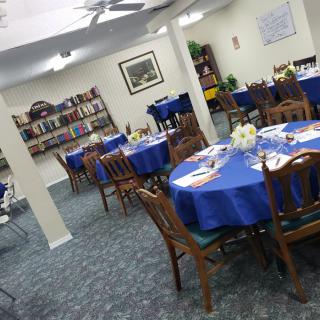 A cozy dining area with blue tablecloths and bookshelves.