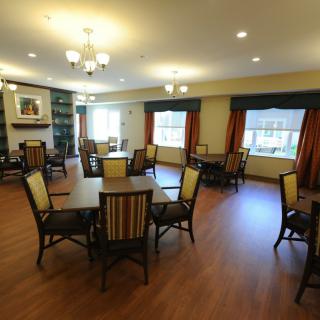 A cozy dining area with several tables and chairs, featuring wooden floors and warm lighting.