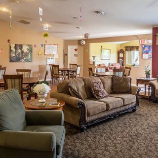 A cozy living room with sofas and a dining area in the background.
