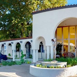 A Mediterranean-style house featuring prominent arches, a courtyard garden, and a central statue.
