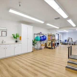 A spacious and well-lit rehabilitation center equipped with various fitness tools for physical therapy.