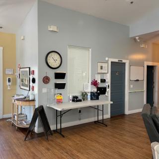 A bright interior space featuring a table with decorative items and a wall clock.