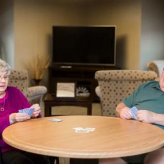 An elderly couple playing cards together in a cozy living room setting.