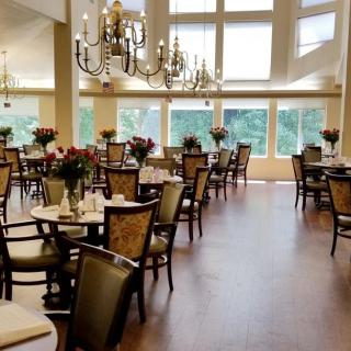 An elegant dining room with chandeliers, large windows, and neatly arranged tables and chairs.