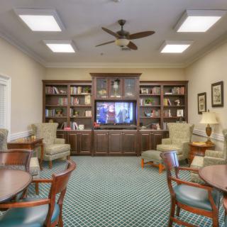 A cozy library room featuring bookshelves, a television, and comfortable seating.