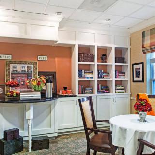 A well-decorated kitchen area with shelves, chairs, and a table adorned with flowers.