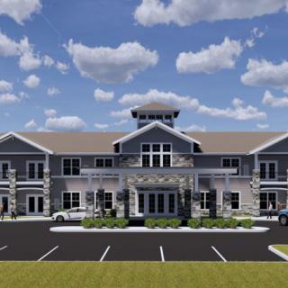 A front view of a large, two-story commercial building with a parking lot and a cloudy sky in the background.