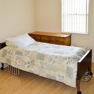A minimalist bedroom with a single bed and wooden dresser.