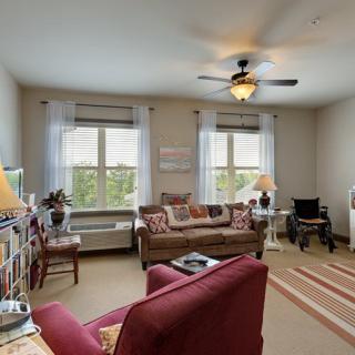 A cozy living room with a sofa, armchairs, and natural light streaming through the windows.