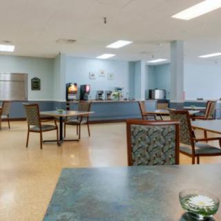 An empty cafeteria with tables and chairs arranged neatly in a spacious dining area.