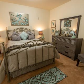 A cozy bedroom with a metal bed frame, a dresser with a mirror, and stylish decor.