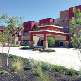 A modern hospital building with landscaped surroundings on a sunny day.