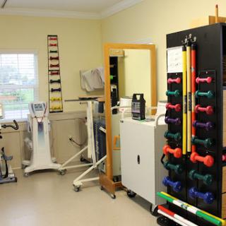 A well-equipped physical therapy room featuring various exercise equipment and weights for rehabilitation.