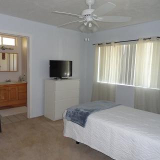 A simple bedroom with a bed, TV, and window with curtains.